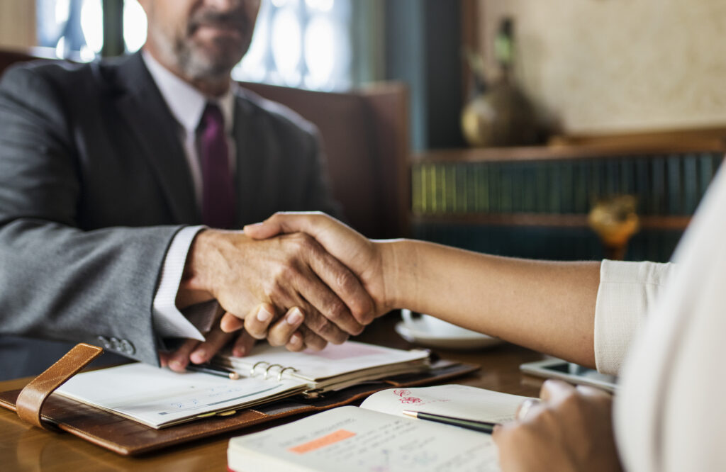 On peut voir deux personnes se serrer la main lors d'un accord contractuel.