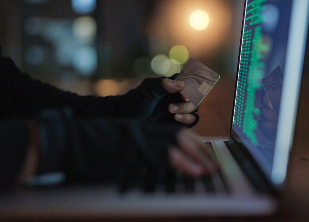 Pirate informatique non identifiable utilisant un ordinateur portable pour pirater un compte bancaire.